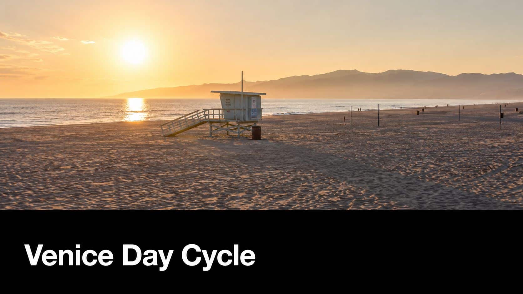 A scenic sunset over the sandy Venice Beach with a solitary lifeguard tower in the foreground.