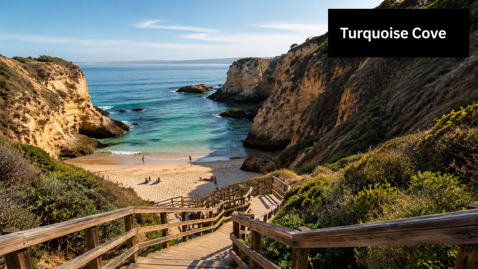 A scenic wooden stairway descending toward a pristine turquoise beach surrounded by rocky cliffs and foliage.
