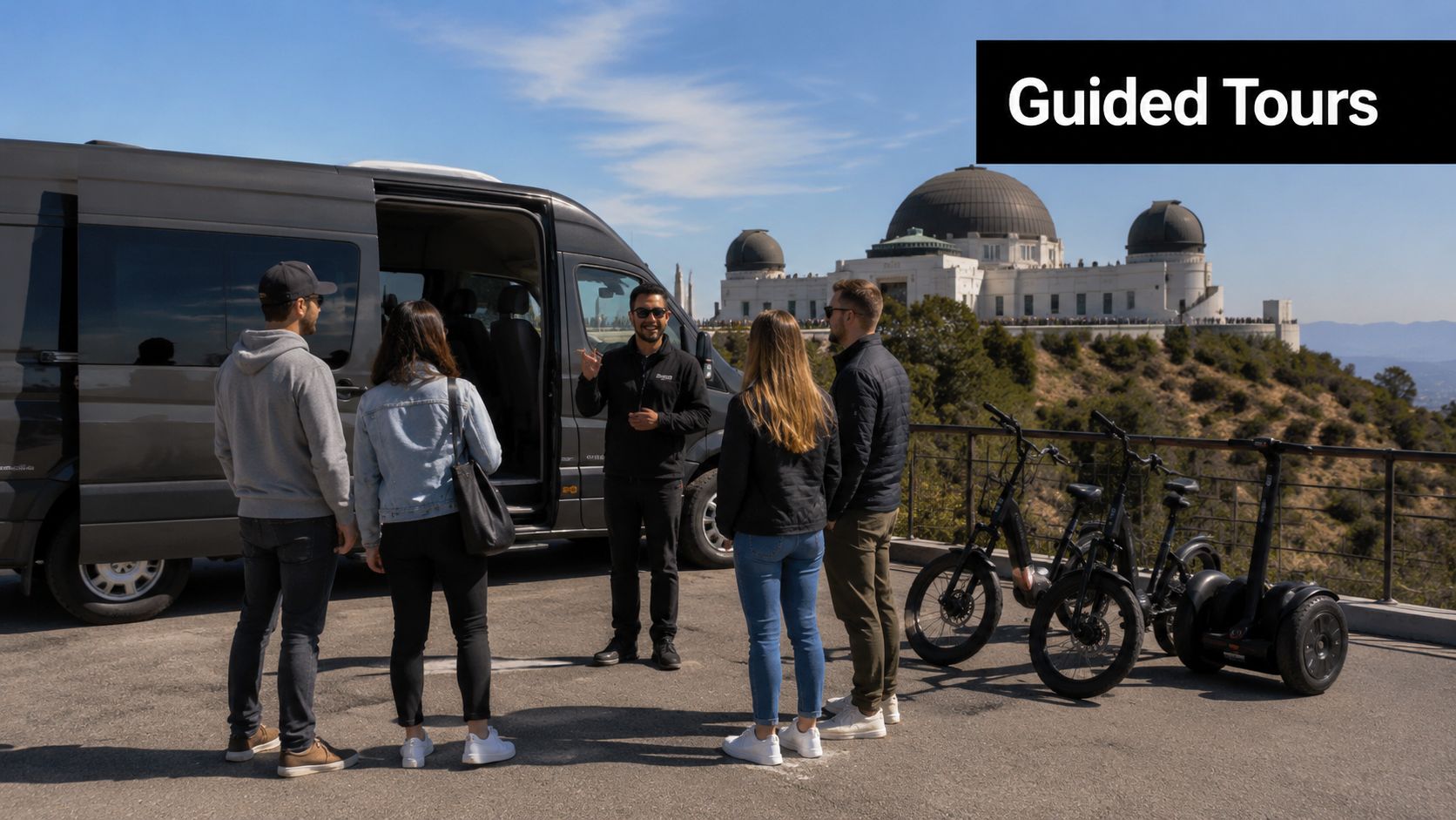 A tour guide talks to a small group standing by a van with the Griffith Observatory in background.