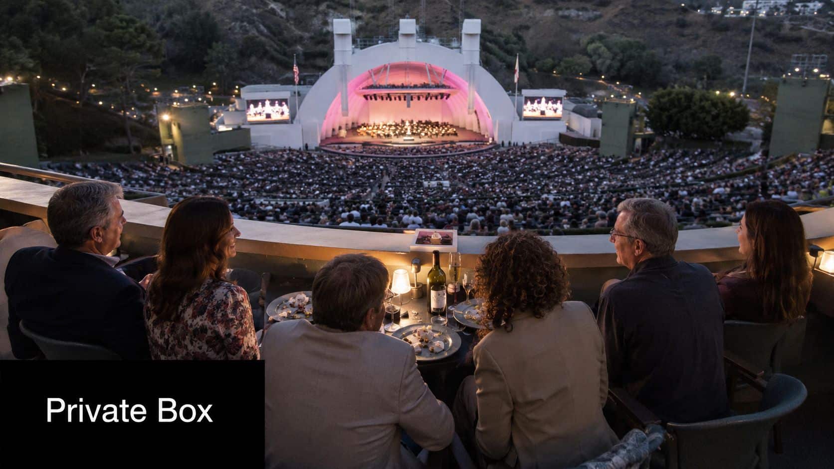 A group of people dining in a private box at the Hollywood Bowl during a concert.