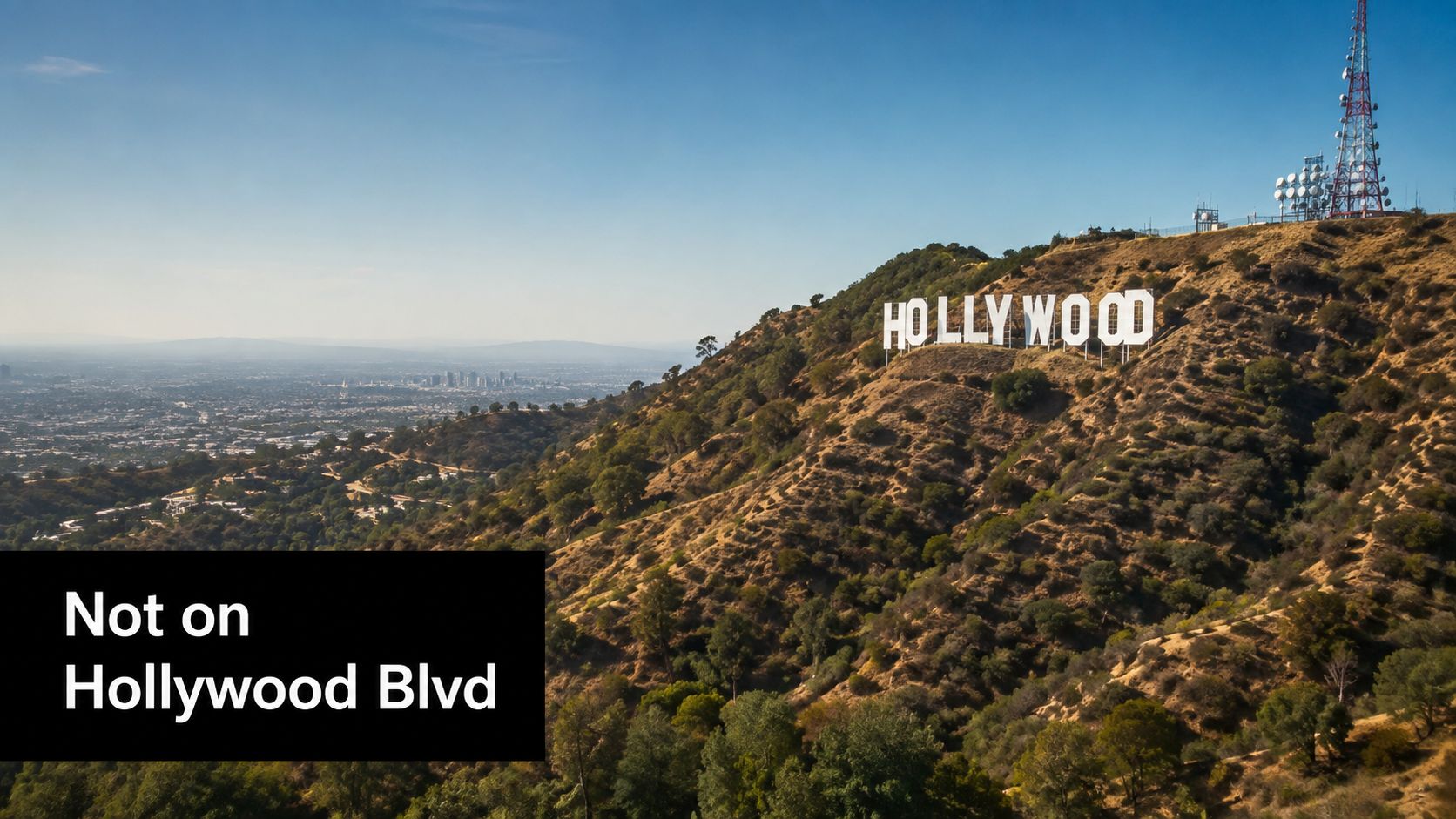 The iconic Hollywood sign sits on a hillside overlooking the sprawling cityscape of Los Angeles below.